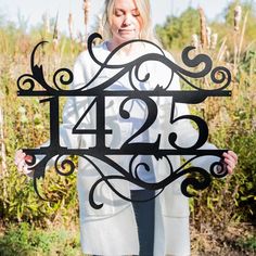 a woman holding up a metal sign with the number twenty four in it's center