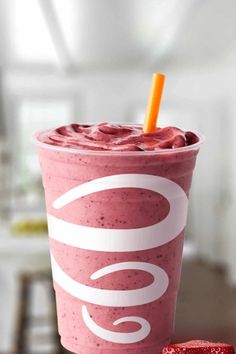 a pink drink sitting on top of a table next to a piece of red fruit