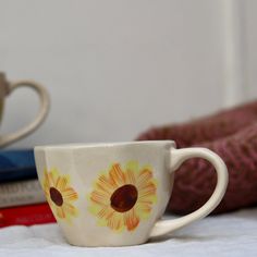 a white coffee cup with yellow flowers painted on it