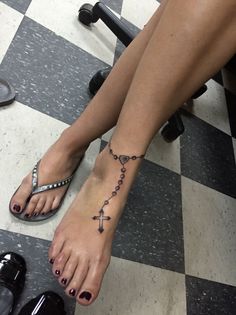 a woman's foot with a cross tattoo on it