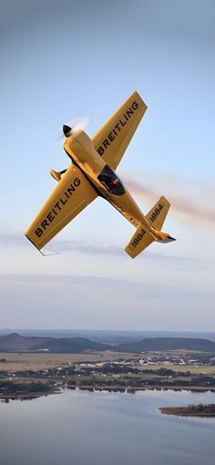 a small yellow plane flying over the water