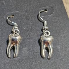 a pair of silver earrings with a tooth on it