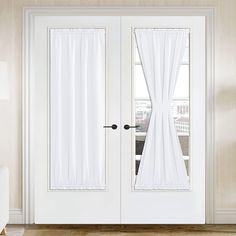 two white doors with curtains on them in front of a window