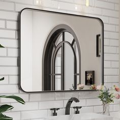 there is a large mirror on the wall above two sinks and a vase with flowers in it