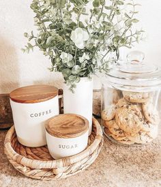 some cookies and flowers are sitting on a counter next to a glass jar with the word coffee written on it