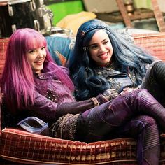 two women with purple hair sitting on a couch next to each other and smiling at the camera