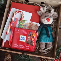 a christmas gift box with a stuffed reindeer and candy canes in it, along with other holiday items