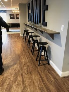 a man standing in front of a bar with stools and a sign on the wall