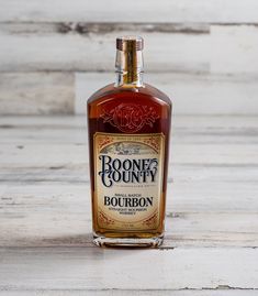 a bottle of booze county bourbon sitting on a table next to a wooden wall