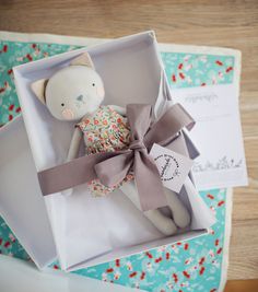 a stuffed animal in a box with a ribbon