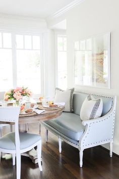 a dining room table and chairs with plates on them in front of two windows that look out onto the outdoors