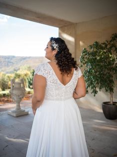 a woman in a white wedding dress looking out over the hills from her patio area