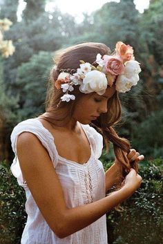 a girl with flowers in her hair is looking down at her cell phone while wearing a flower crown