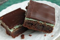 two pieces of cake sitting on top of a white plate with chocolate frosting and mint