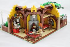 a lego model of a medieval castle with people sitting in the doorway and eating food