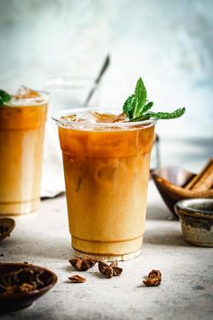 two glasses filled with iced tea sitting on top of a table