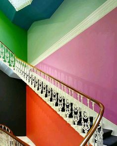 a stair case with chandelier hanging from it's sides next to a multicolored wall