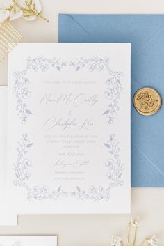 the wedding stationery is laid out on top of blue envelopes and white flowers