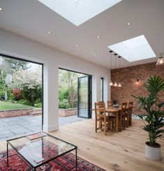 a living room filled with furniture next to a brick wall covered in windows and doors