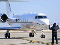 a man standing in front of an airplane on the tarmac with his hand up