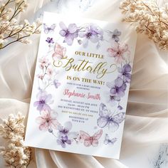 a little butterfly is on the way baby shower card with purple flowers and gold foil lettering