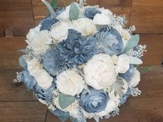 a bridal bouquet with blue and white flowers on a wooden floor in front of a wall