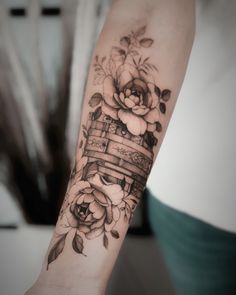 a woman's arm with flowers and a basket tattoo on her left arm, which is decorated with roses