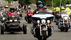 a group of motorcyclists are riding down the street in front of police