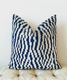 two blue and white pillows sitting on top of a couch