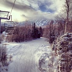 a ski lift going up the side of a snow covered mountain with trees on it