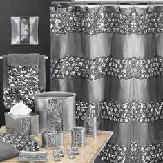 a black and white bathroom with silver accessories on the counter next to the shower curtain