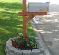 a mailbox in the middle of a flower bed with flowers growing out of it