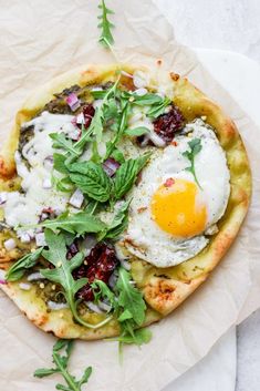 an egg is on top of some type of pizza with greens and other toppings