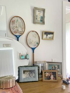 there are three tennis racquets on the wall next to pictures and frames