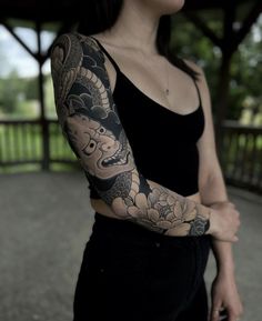 a woman with a dragon tattoo on her arm and arms is posing for the camera