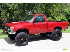 a red pick up truck parked in front of some trees