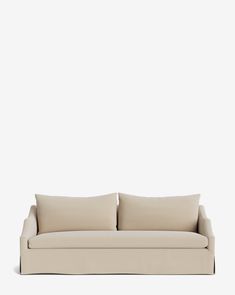 a beige couch with two pillows on it's back and one arm facing the camera