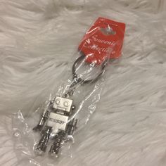 a red and white robot shaped keychain on top of a white furry surface