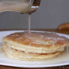 a stack of pancakes with syrup being poured on top