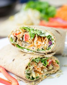 two wraps filled with meat and veggies on top of a white plate next to vegetables