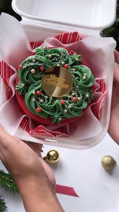 someone is holding a decorated christmas cookie in a box