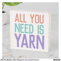 a sign that says all you need is yarn next to a potted green plant