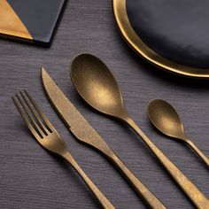 the gold utensils are sitting next to each other on the black tablecloth