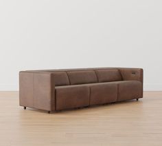 a brown couch sitting on top of a hard wood floor next to a white wall