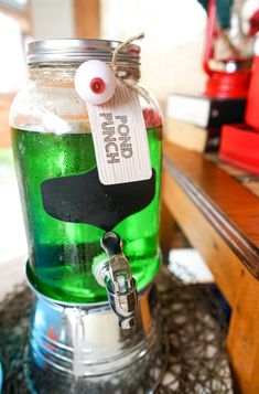 a glass jar filled with green liquid sitting on top of a table