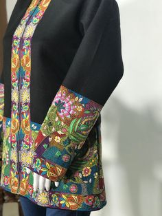 a mannequin wearing a black jacket with colorful designs on it's sleeves