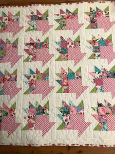 a pink and green quilt on a wooden table