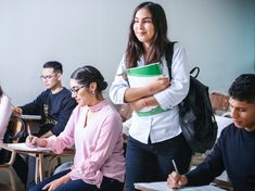 a group of people sitting at desks with books and papers in front of them