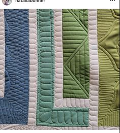 a close up of a quilt on the back of a bed with green and blue strips