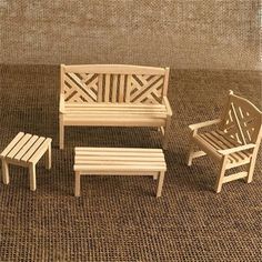 three miniature wooden chairs and a small table on a carpeted area with a wall in the background